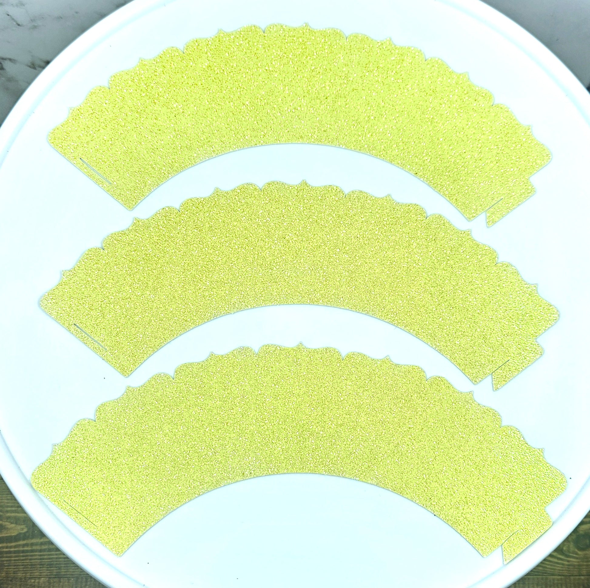 Three yellow paper cups on a white plate with a wooden surface underneath.
